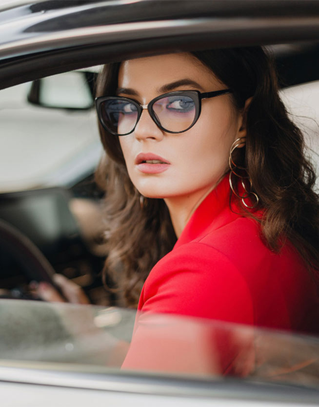 Mujer mirando por la ventana de su carro con gafas